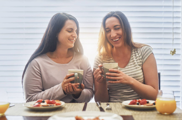 Змушуючи один одного сміятися вранці. дві молоді жінки снідають разом вранці вдома
 - Фото, зображення