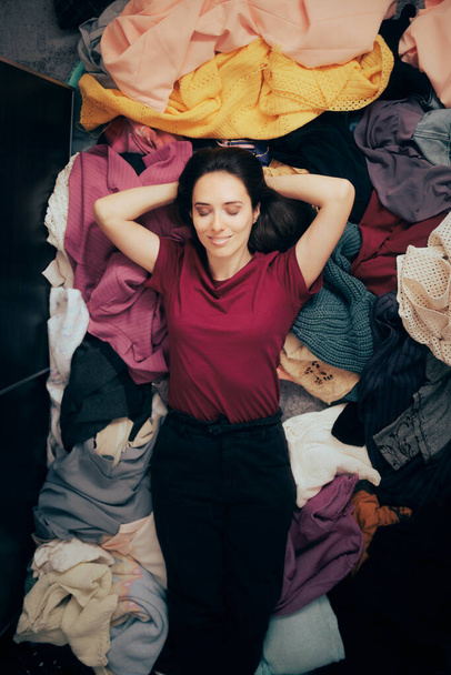 Happy Woman Loving Fashion Sitting on a Pile of Clothes - Fotó, kép