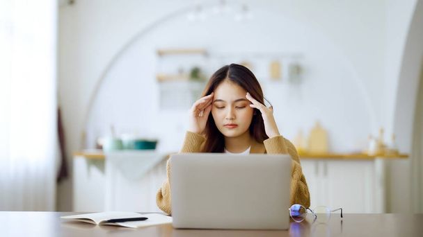 Koncepcja zespołu biurowego. Przepracowana młoda, zmęczona Azjatka odczuwająca ból głowy, mająca problemy z wzrokiem po pracy na laptopie. Stres dorosłych kobiet biznesowych cierpiących na zmęczenie w domu - Zdjęcie, obraz