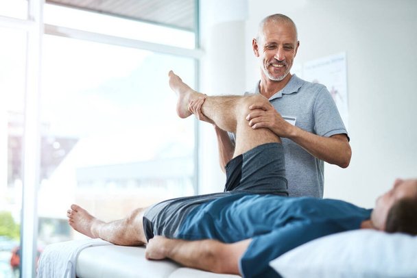 Well heal your injury in no time. Low angle shot of a handsome male physiotherapist treating a patient - Foto, imagen