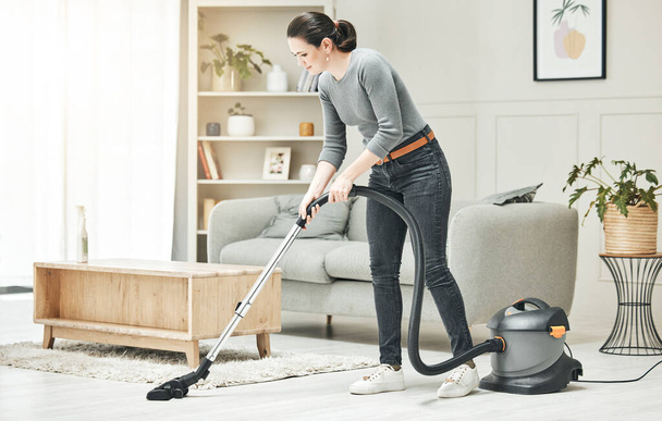 Vacuuming, cleaning and housework done by a mother, house wife or girlfriend using a vacuum cleaner. Stay at home mom, maid or housekeeper doing household chores and tidying in a modern living room. - Zdjęcie, obraz