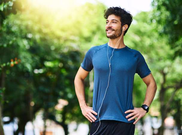 Getting started on a healthier lifestyle. a sporty young man listening to music while exercising outdoors - Fotoğraf, Görsel