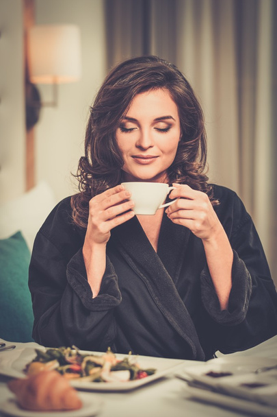 Όμορφη γυναίκα παίρνει πρωινό σε ένα δωμάτιο ξενοδοχείου - Φωτογραφία, εικόνα