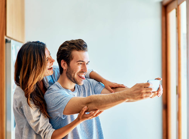 Come on, make a silly face. a happy young couple taking a selfie together at home - Foto, Imagem