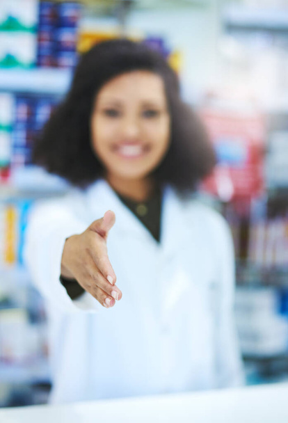 Hello, Im here to help. a young woman extending her arm for a handshake at the counter of a pharmacy - Foto, immagini