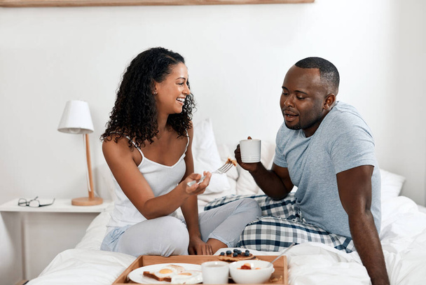 Now that was a satisfying breakfast. a cheerful young couple enjoying breakfast in bed together at home during the day - Fotoğraf, Görsel