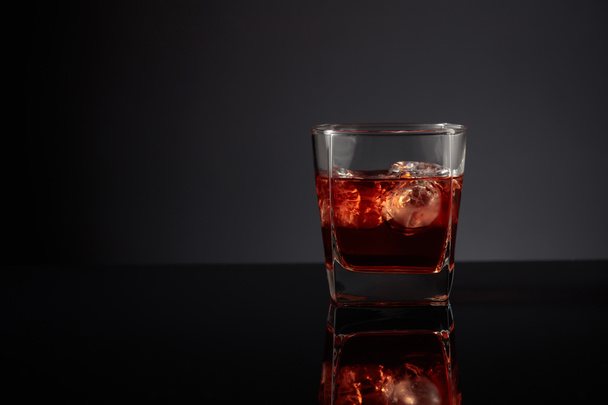 Whiskey with ice on a black reflective background. Copy space. - Фото, зображення