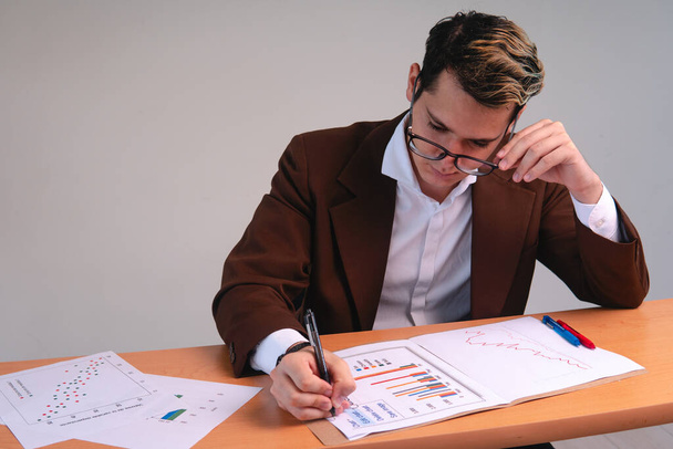 Business man reviewing important charts. Business executive working at his desk analyzing data. Data analyst. Blond man dressed in a suit and glasses. High quality photo - Photo, image