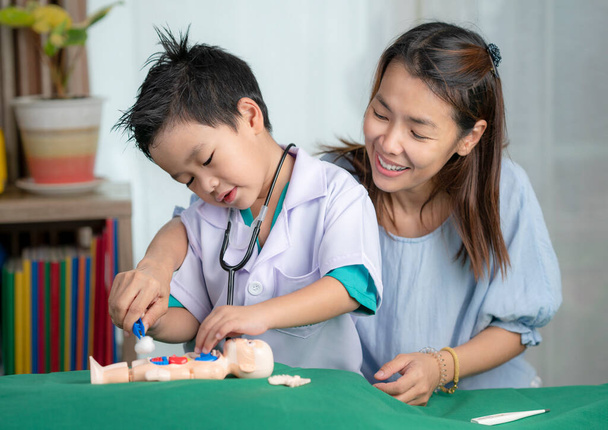 Азійська мати і тер'єр діти грають в топінг лікаря, мрія студента - лікар. - Фото, зображення
