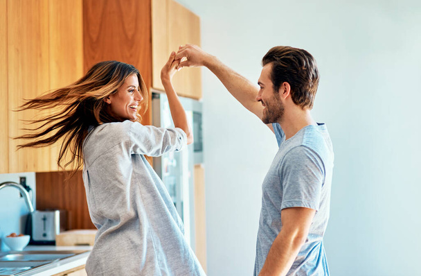 Now give me a big twirl. a happy young couple dancing together at home - Foto, afbeelding