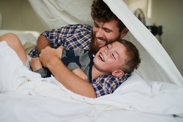 Here comes the tickle monster. a handsome young man and his son playing on the bed at home - Фото, зображення