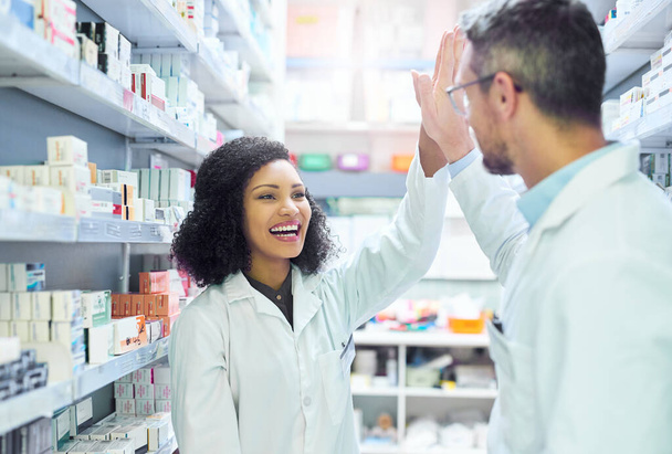 Winners in the wellness industry. a mature man and young woman giving each other a high five while working in a pharmacy - Foto, afbeelding