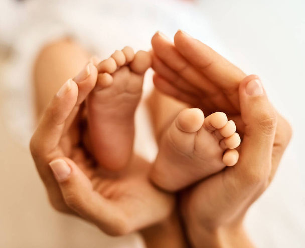 Крошечные ножки, которые сделали ее жизнь полной. мать бережно держит своих младенцев на ногах - Фото, изображение