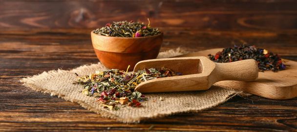 Bowl and scoop with dry tea leaves on wooden table - Foto, Bild
