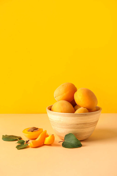 Bowl of delicious ripe apricots on color background - Fotó, kép