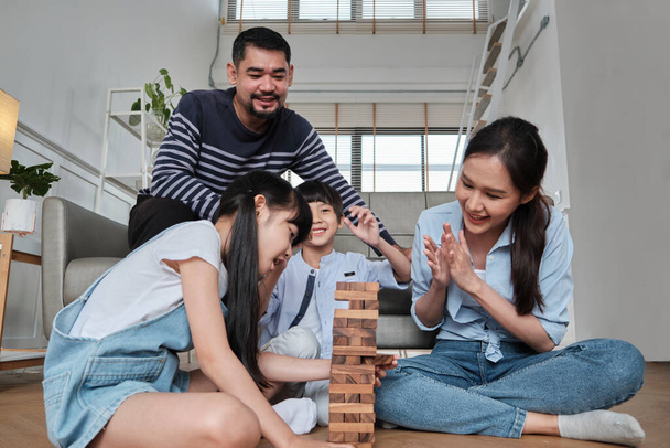 Happy Asian lovely Thai family activity, parents, dad, mum, and children have fun playing and joyful wooden toy blocks together on living room floor, leisure weekend, and domestic wellbeing lifestyle. - Foto, Imagen