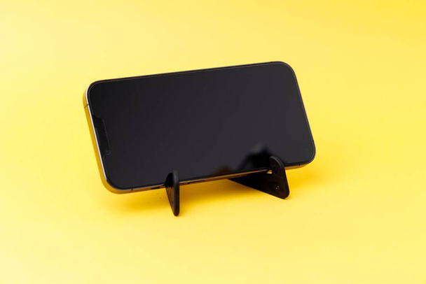 A smartphone with a tiny stand isolated on a yellow background - Zdjęcie, obraz
