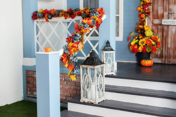 Ház bejárati lépcső díszített őszi ünnepek, őszi virágok és sütőtök. Hangulatos veranda a ház fából készült lámpákkal ősszel. Halloween design otthon sárga őszi levelek és lámpák.  - Fotó, kép
