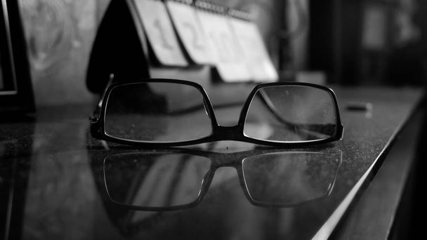 A closeup grayscale shot of glasses on the table full of dust - Фото, изображение
