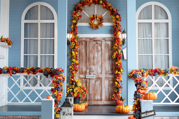 Дизайн Хэллоуина с желтыми осенними листьями и фонарями. Лестница украшена для осенних праздников, осенних цветов и тыкв. Уютное деревянное крыльцо дома с тыквами осенью - Фото, изображение