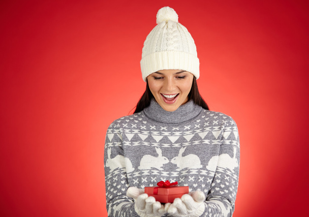 Mädchen in Winterbekleidung betrachtet kleine Geschenkbox - Foto, Bild
