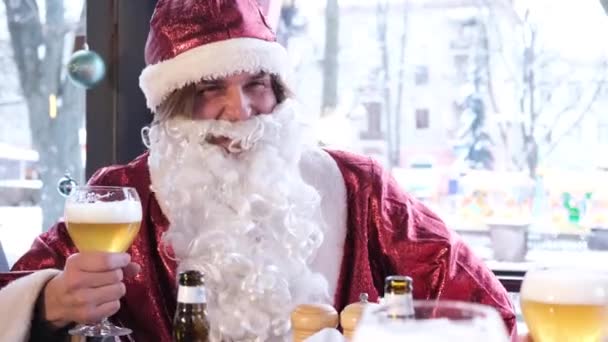 Friends in Santa Claus costumes are having fun at a New Years party, drinking beer in a pub. Celebration of Christmas and New Year 2023 - Video