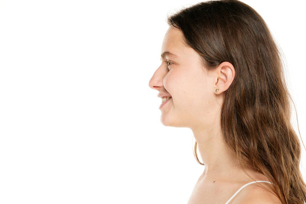 Profile of a young smiling woman without makeup on a white background. - Foto, Bild