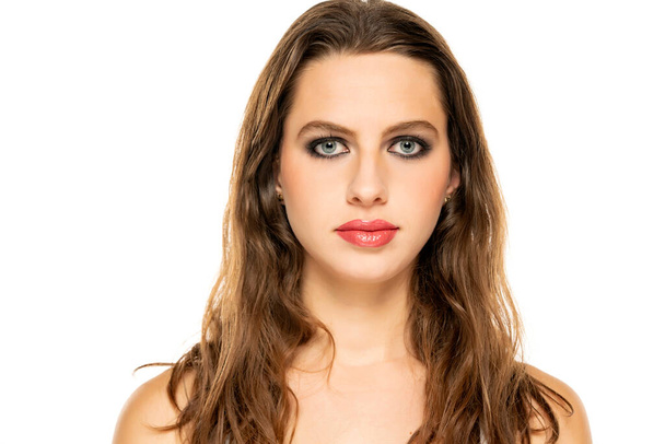 Beautiful serious woman with make up and wavy hair on a white background. - 写真・画像