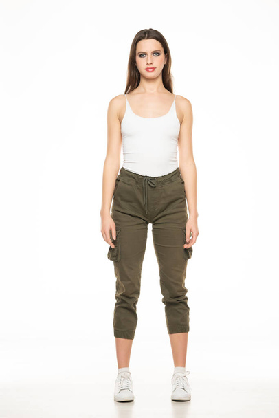 Young woman with three-quarter pants and shirt posing in the studio on white background. - Foto, imagen