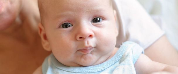 Close-up detail portrait of cute little peaceful newborn baby boy child face with beautiful open eyes. Love and family emotion - 写真・画像