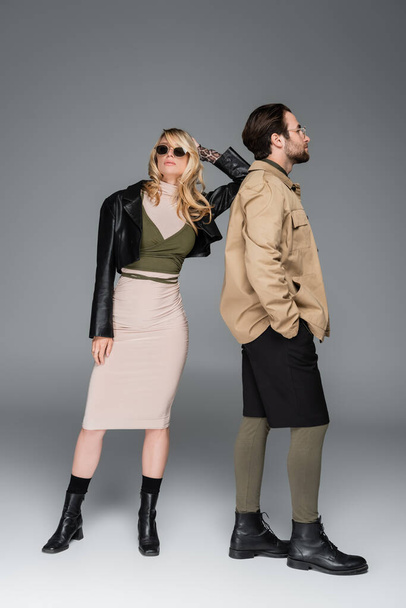 full length of stylish couple in autumnal outfits and posing together on grey - Foto, immagini