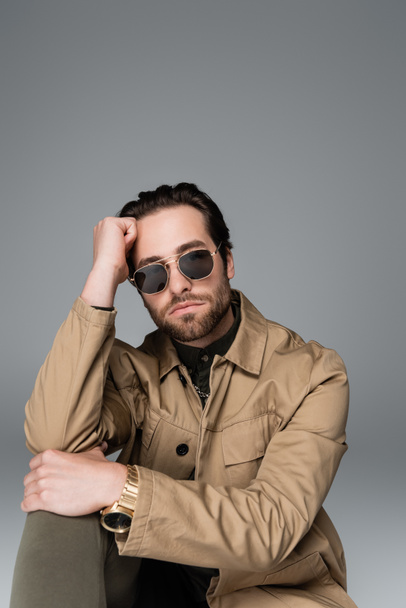 bearded man in stylish outfit and sunglasses looking at camera isolated on grey - Foto, Bild