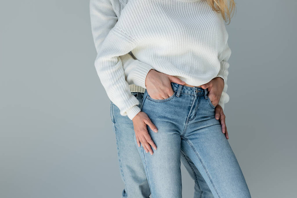 cropped view of couple in white sweaters and jeans posing isolated on grey  - Photo, image