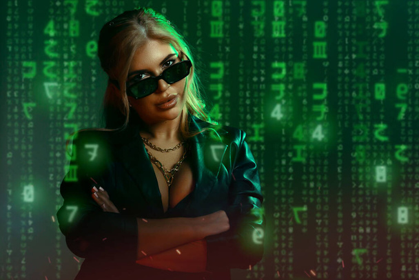 Великолепная женщина в костюме матрицы. Черная кожа и отражение кода в очках в зеленом свете и тени матрицы. Концепция кибертехнологий, будущее и прогресс - Фото, изображение