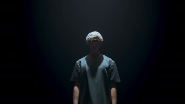 Man wearing virtual reality goggles in light. Unknown cyber player in dark room. Blonde guy immerse metaverse console simulation in futuristic headset. Experience smart entertainment in studio shadow - Filmati, video