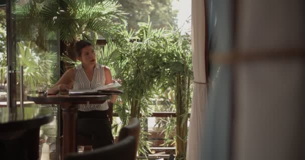 Business woman working alone in a cafe bar terrace on a sunny day ordering from waiter - Imágenes, Vídeo