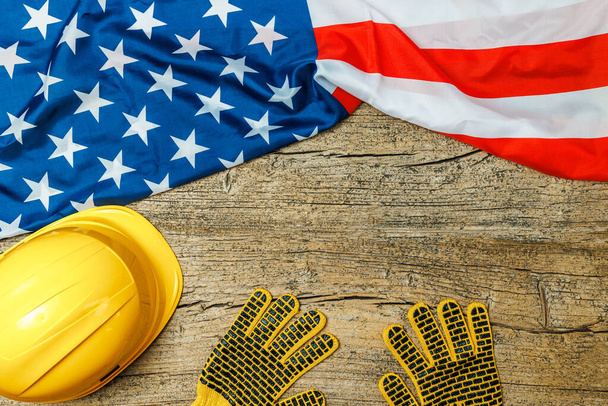 Yellow helmet and gloves with American flag on old wooden table, space for text. Labor day - Photo, Image