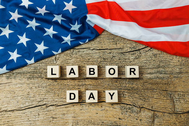 US American flag with wooden cubes with word Labor day on old wooden background. Labor day celebration.  - Fotó, kép