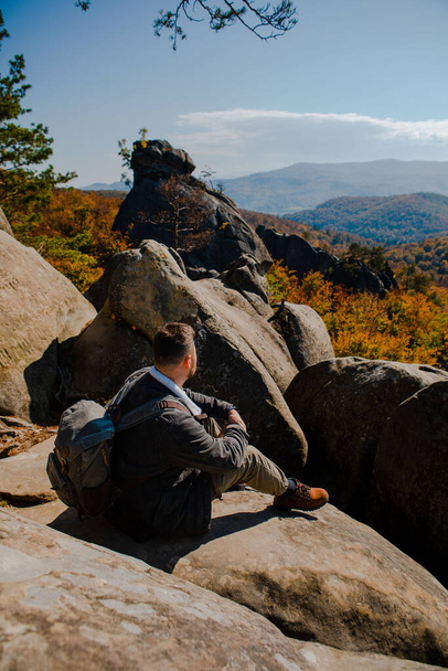 man hiker sitting on the rock enjoying autumn landscape copy space - Foto, Bild