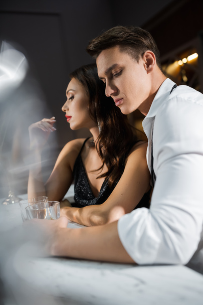 Man in shirt holding glass near elegant girlfriend in bar  - Photo, image