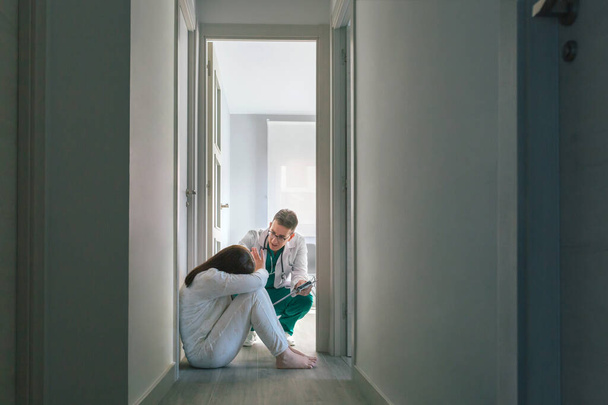 Γιατρός προσπαθεί να βοηθήσει γυναίκα ασθενή με ψυχική διαταραχή που αρνείται βοήθεια στο νοσοκομείο - Φωτογραφία, εικόνα