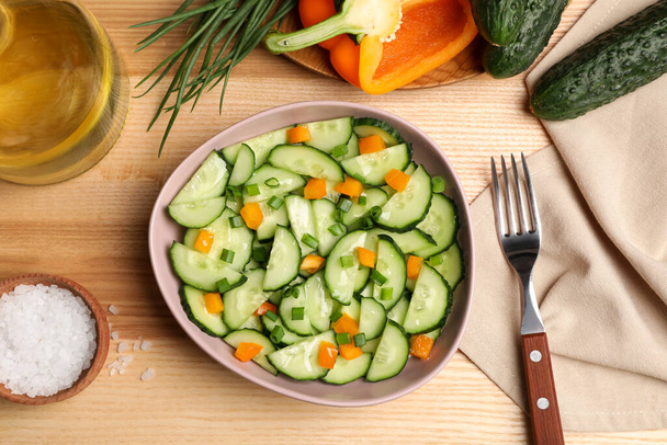 Tasty fresh salad with cucumber served on wooden table, flat lay - Fotografie, Obrázek