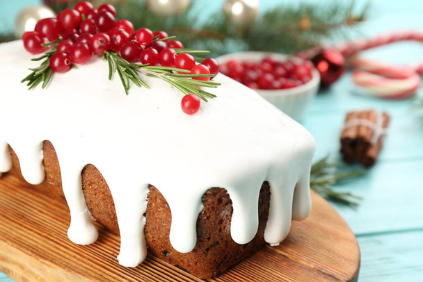 Traditional classic Christmas cake decorated with cranberries and rosemary on turquoise table, closeup - Foto, Imagen