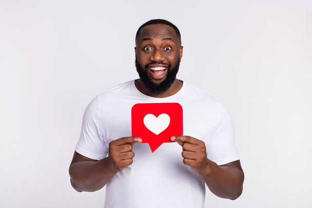 Photo of excited funky man wear casual t-shirt holding heart like sign isolated white color background. - Foto, Bild