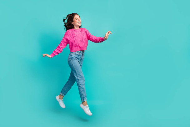 Full size photo of nice gorgeous girl dressed pink pullover denim jeans sneakers flying walking isolated on turquoise clor background. - Zdjęcie, obraz