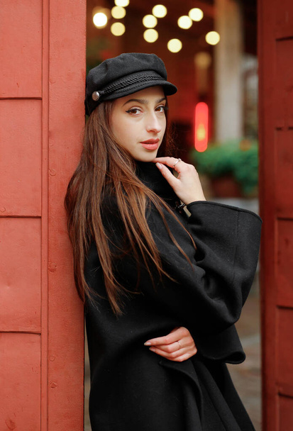 Luxury girl in a black coat and hat posing on the street. - Фото, зображення