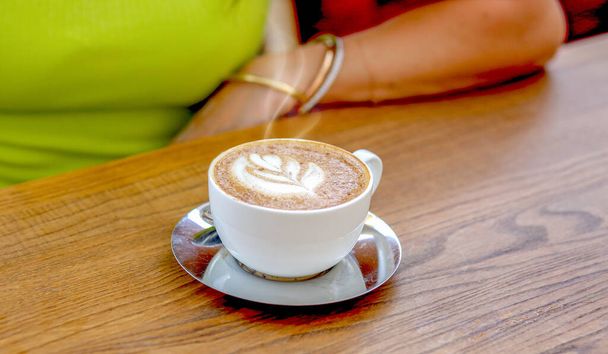 Baner with a cup of coffee with cream on a wooden brown table. Cappuccino. Natural coffee beans. Good morning concept. - Photo, image