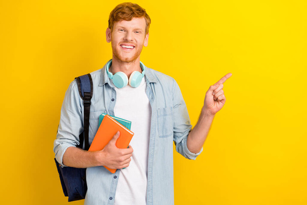 Photo of cheerful positive boy arm hold planner diary direct empty space offer online courses learning isolated on yellow color background. - 写真・画像