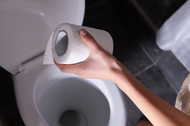 woman holding toilet paper in restroom. abdominal pain - Photo, image