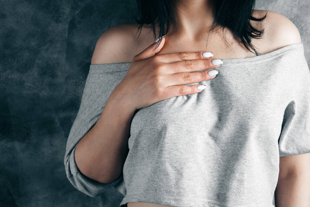 a young woman has a chest pain on a gray background - Fotoğraf, Görsel